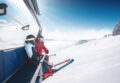 Skifahrer fährt durch tiefen Pulverschnee in den Alpen vor verschneiten Bergen und blauem Himmel.